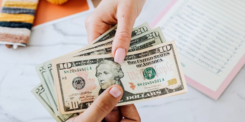 Woman holding Money | Buy Nothing New Day versus Green Friday vs Black Friday