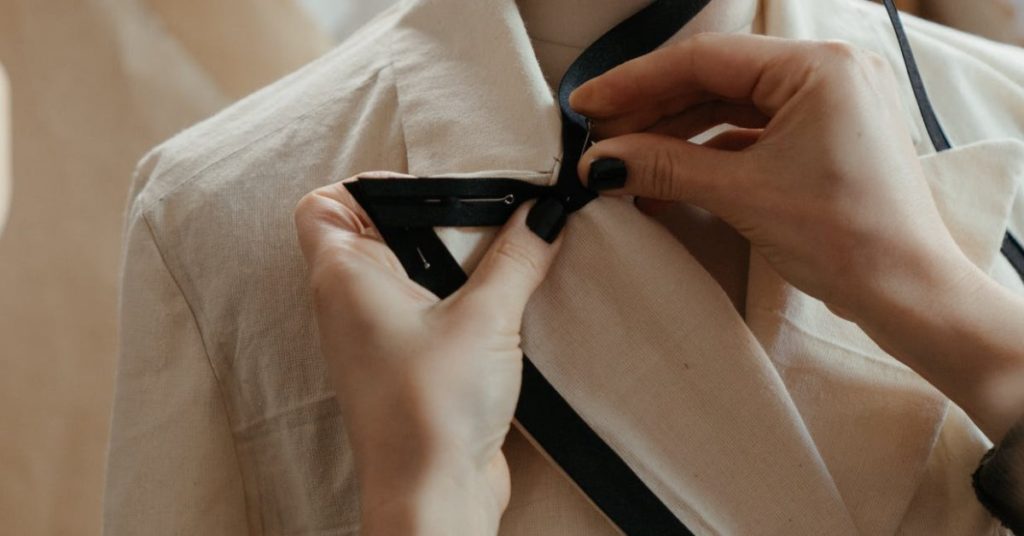 Woman altering a black and white jacket | What does an alterations specialist do?