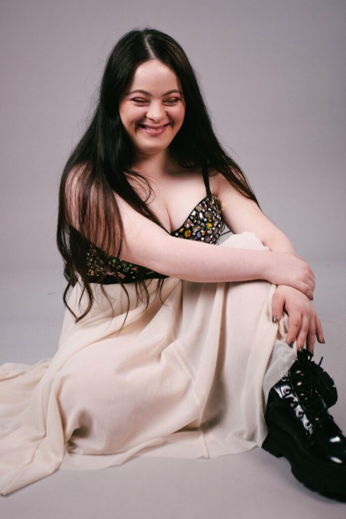 Ellie a down syndrome model from Zebedee wears a bejewelled  bustier crop top, with a tulle skirt and chunky boots