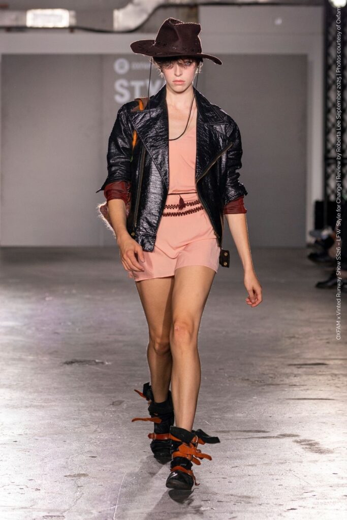 Cassidy Clover in 90s boho-grunge playsuit with leather jacket, scrunchy slouchy buckle boots and hat – Oxfam x Vinted Fashion Week.”