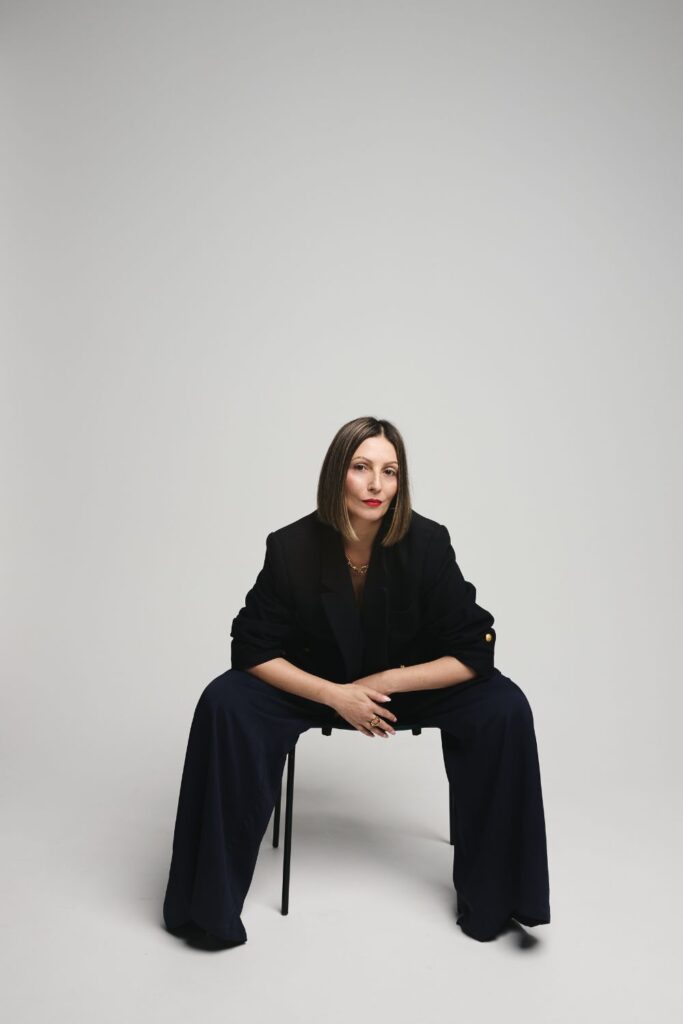 Roberta Lee - Sustainable Stylist with Values - London. Seated in powerful position wearing sustainable clothes in Navy. Elegantly styled.